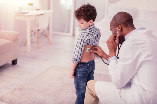 Muchacho agradable mostrando su espalda al médico — Foto de Stock