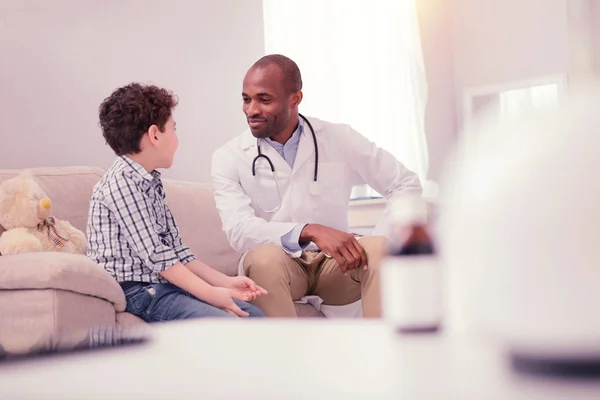 Cheerful Afro American doctor listening to a boy — Stock Photo, Image