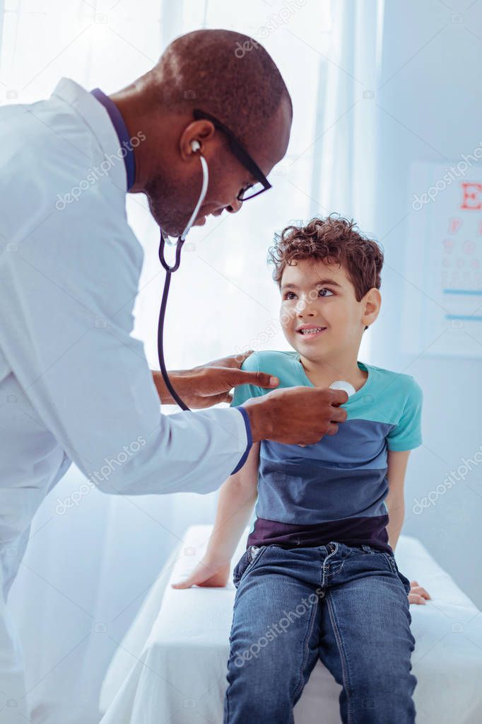 Joyful positive doctor enjoying working with children