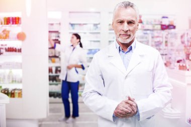 Kollarını katlama üniformalı ciddi gri saçlı bilim adamı