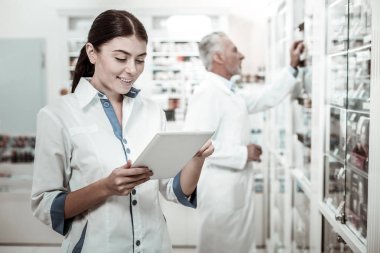 Güzel esmer eczacı holding tablet ilaç mesafeden ararken