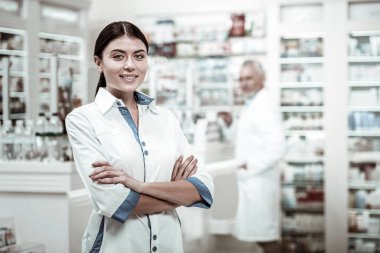 Eczanede çalışan beyaz önlük giymiş esmer ışınlama çekici kadın