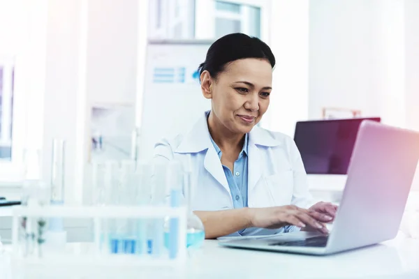 Mujer positiva alegre sentado delante de la computadora portátil — Foto de Stock