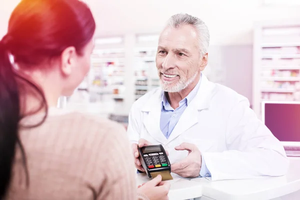 Smiling pharmacist proposing woman a payment terminal — Stock Photo, Image