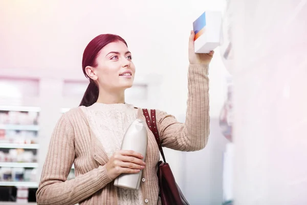 Atractivo cliente femenino comprar champú y pastillas — Foto de Stock