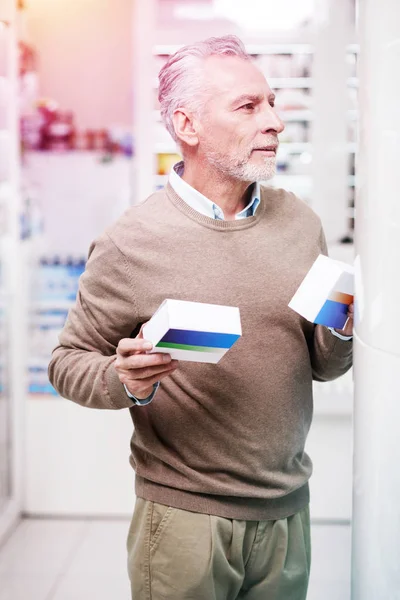 Hesitating buyer holding medications in two hands — Stock Photo, Image