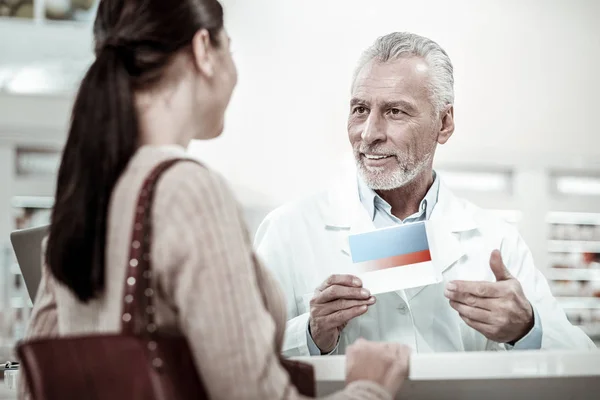 Agradable farmacéutico profesional maduro hablando con su cliente de cabello oscuro — Foto de Stock