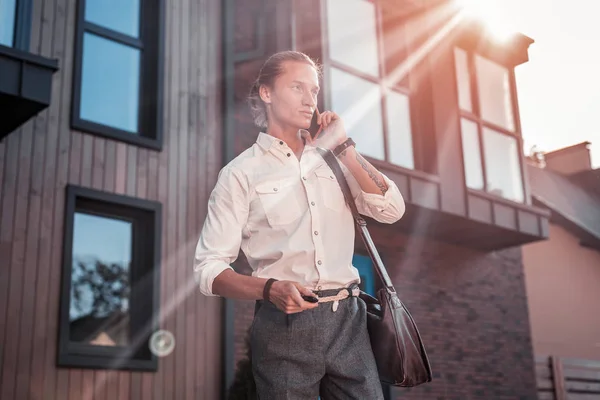 Appealing stylish man with tattoo on his hand feeling busy on the way to office