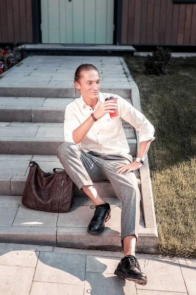 Schöner stilvoller Mann sitzt auf der Veranda, während er auf seine Freundin wartet — Stockfoto