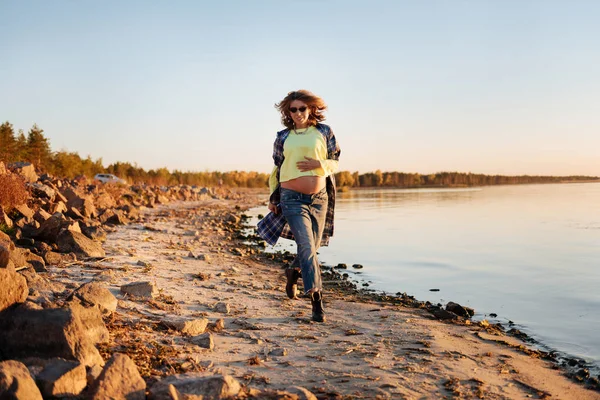 Aktív terhes nő a napnyugtakor a tengerparton fut — Stock Fotó
