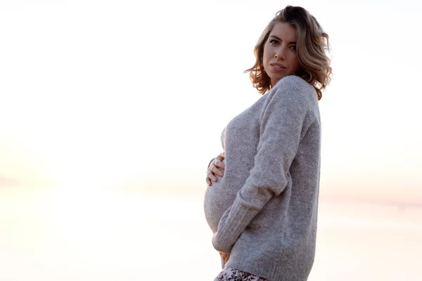 孕妇在毛衣举行她的肚子 — 图库照片