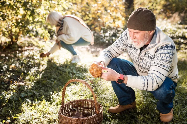 Positivo bom homem colocando um cogumelo na cesta — Fotografia de Stock