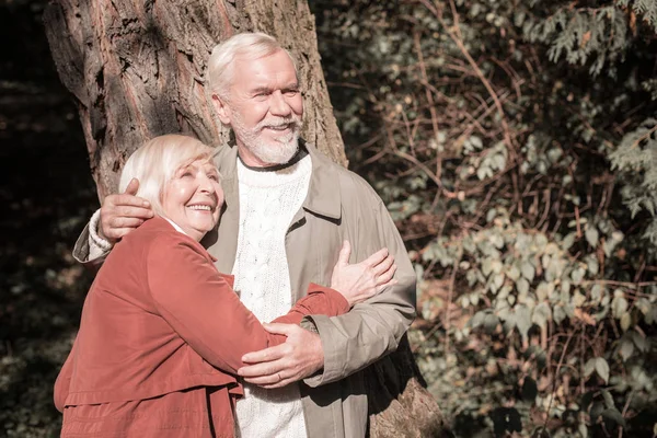 Счастливая парочка пенсионеров, стоящих у дерева — стоковое фото