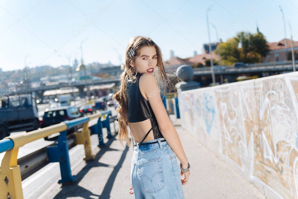 Stylish young woman wearing high-waist baggy jeans and leather top