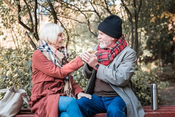 Позитивная пожилая женщина предлагает яблоко своему мужу — стоковое фото