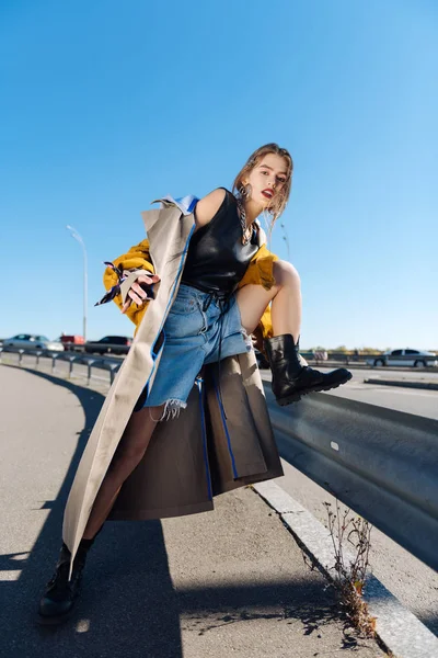 Flaco modelo de moda posando cerca del puente con abrigo largo —  Fotos de Stock