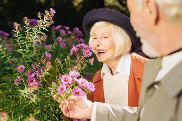 Positiv glad alderen kvinde nyder blomster lugt - Stock-foto