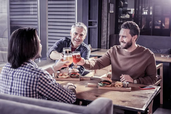 Alegre jóvenes machos tocando bocales con cerveza — Foto de Stock