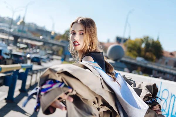 Film video. Dark-haired beautiful young fashion blogger filming her video in new beige coat