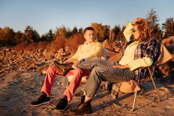 Mladá rodina sedí na skládací křesla na západ slunce — Stock fotografie