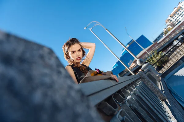 Baixo ângulo de mulher bonita com penteado agradável em pé na ponte — Fotografia de Stock