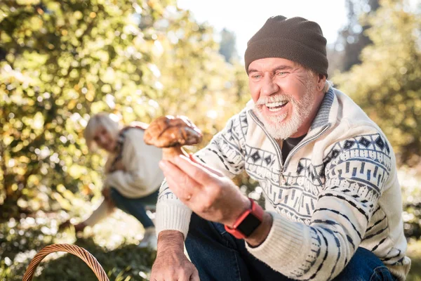 Agradável homem idoso alegre olhando para o cogumelo — Fotografia de Stock