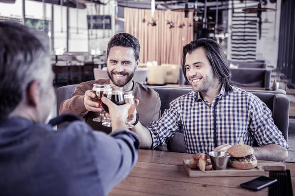 Guapo morena hombre tocando gafas con amigos — Foto de Stock