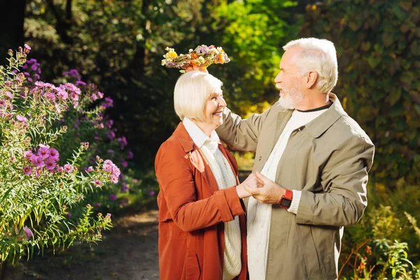 Hombre anciano alegre sosteniendo una hermosa corona de flores — Foto de Stock