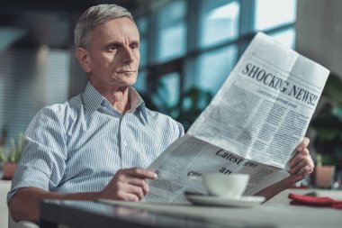 Gazetede görünen özenli gri saçlı yaşlı adam