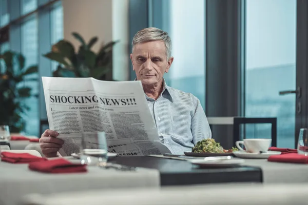 Delighted pensioner reading shocking news on daily basis