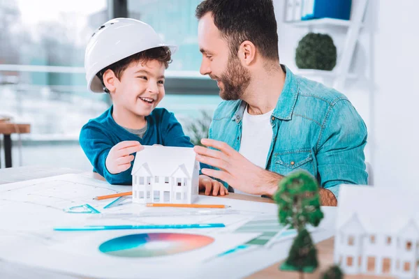 Smiling son and dad making a paper figure together