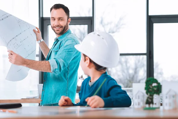 Uomo sorridente che mostra una bozza di progetto a un bambino — Foto Stock