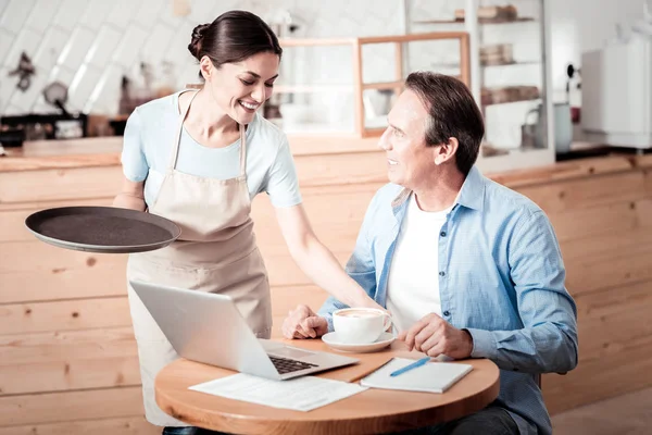 Joyful nice woman putting a cup of coffee on the table — Stock Photo, Image