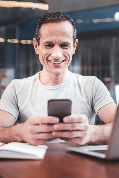 Joven guapo sonriendo mientras mensajea —  Fotos de Stock