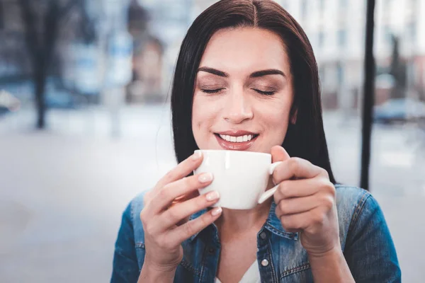 Портрет восторженной девушки, которая пахнет хорошим кофе — стоковое фото