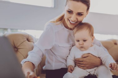 Genç müreffeh anne bebek kızı ile oynarken çevrimiçi çalışıyorsanız