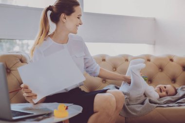 Sevimli gülümseyen bebeğini evde çalışırken eğlenceli iş kadını