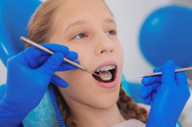 Küçük kız bir diş kliniğinde otururken incelendiğinde onun dişlere sahip olmak