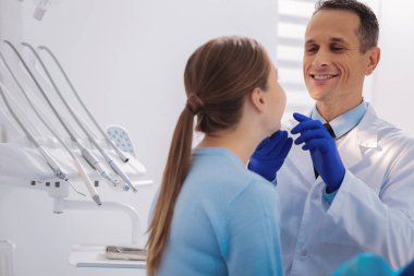 Onun hasta diş denetlerken gülümseyerek olumlu diş hekimi