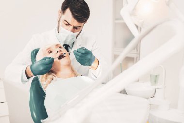 Hastanın muayenesi. Diş hekimleri sandalyede oturan ve profesyonel dental işlemler rahat hissederken getting yaşlı hoş kadın