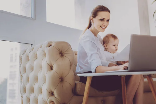 Prosperous sales manager feeling involved in distracting her newborn baby — Stock Photo, Image