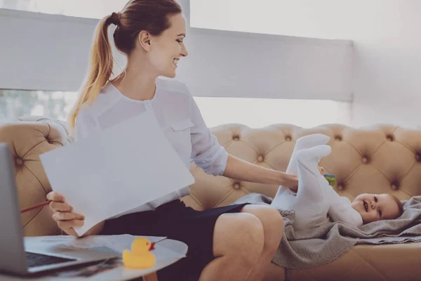 Businesswoman entertaining her cute smiling baby while working at home — Stock Photo, Image