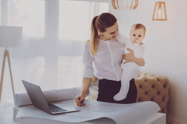 Remote arkitekt ritning Lägenhet planer vid amning hennes små barn — Stockfoto