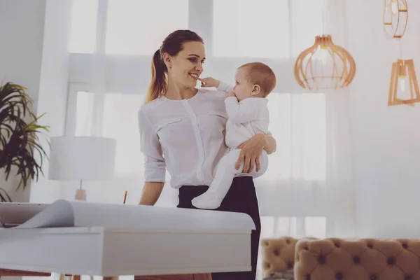 明るい部屋で彼女の勤勉な働く親に触れるかわいい赤ちゃん — ストック写真