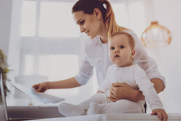 Sweet cute toddler sitting on her mother working in home office — Stock Photo, Image