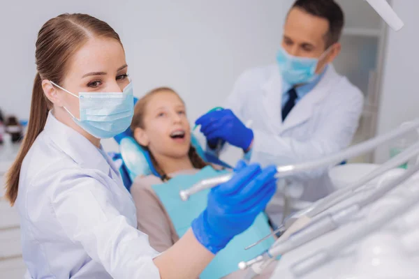 Kvalificerad assistent tar en dental borr samtidigt hjälpa sin kollega — Stockfoto
