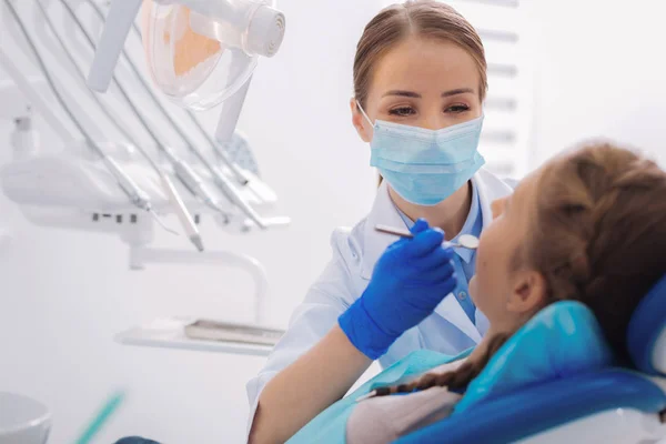 Kind orthodontist holding a dental mirror while working — Stock Photo, Image