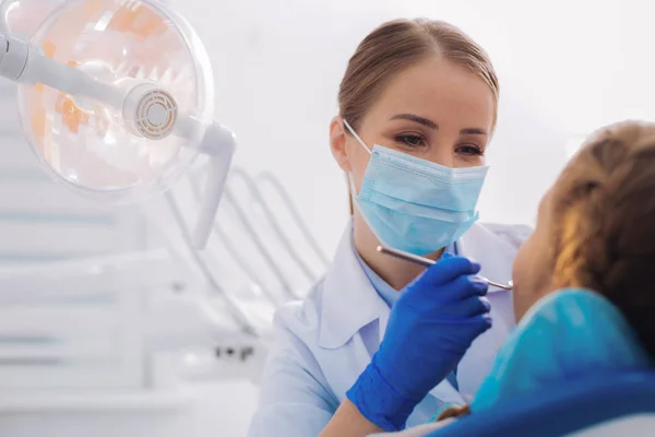 Pediatric dentist looking at the young patient and smiling — Stock Photo, Image