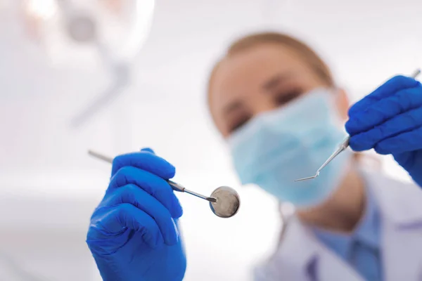 Dentista sério segurando instrumentos enquanto estiver em uma clínica odontológica — Fotografia de Stock