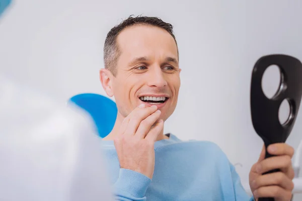 鏡を見ながら自分の歯に触れる幸せな男 — ストック写真